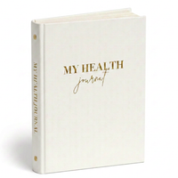 My Health Journal white linen edition with gold lettering, standing upright on a white background